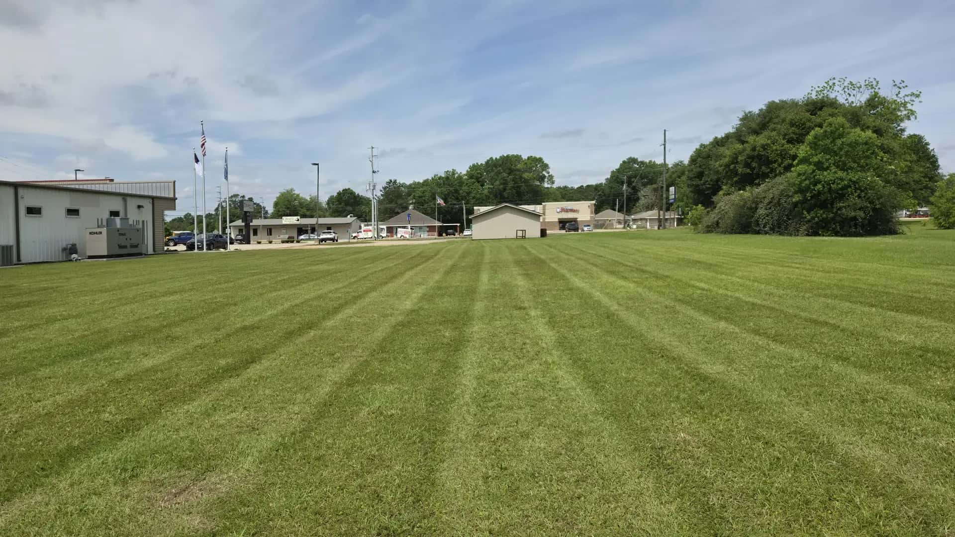 Wide green lawn cut with clean mowing stripes at the correct summer height in Louisiana