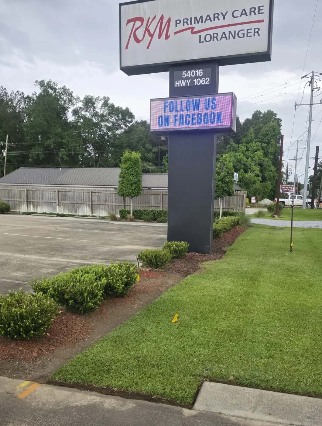Trimmed shrubs and a mowed lawn along the entrance sign at a commercial property in Loranger, LA.