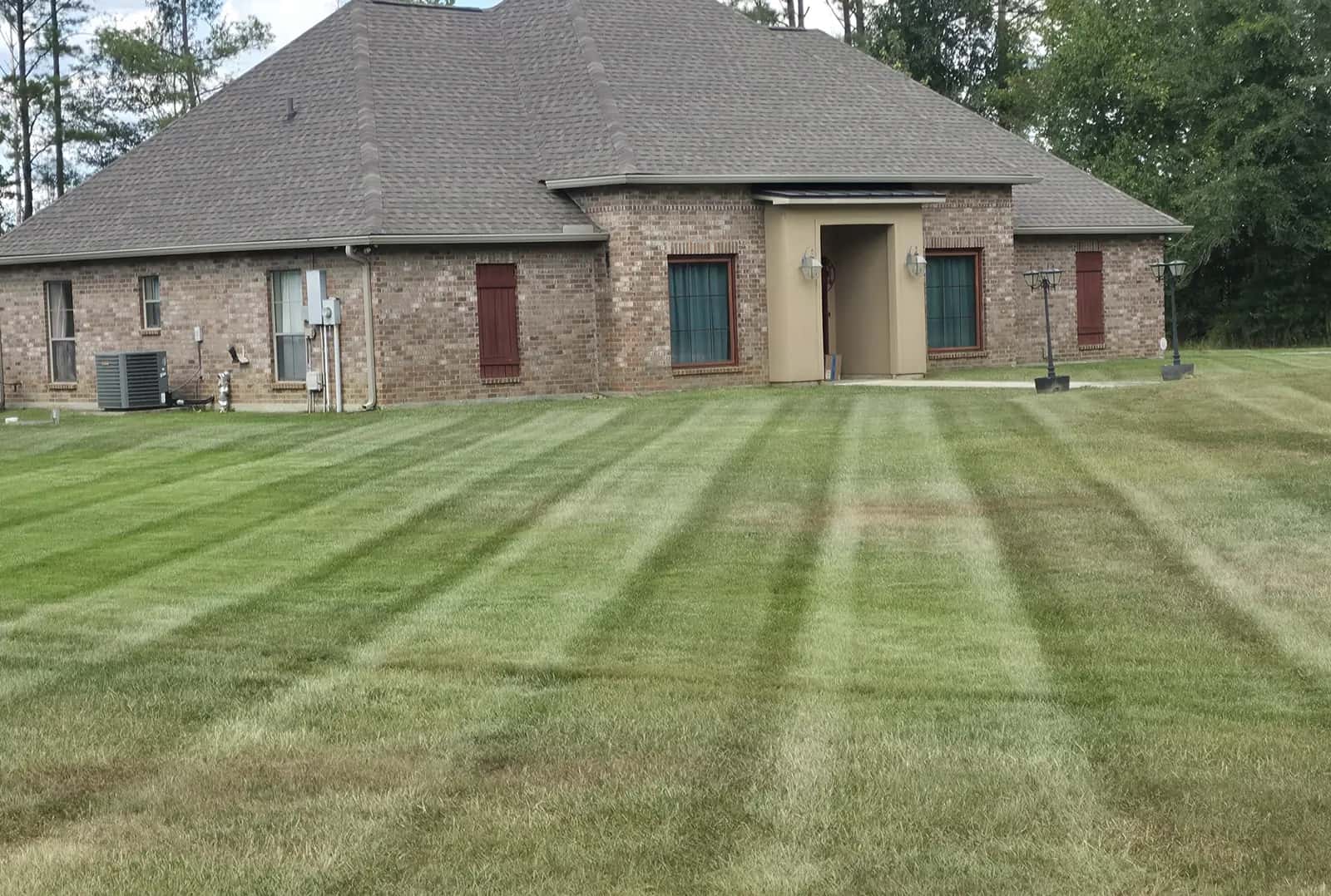 Weekly lawn service on Weiss Rd in Walker, LA: even mowing stripes across the front yard of a brick house.