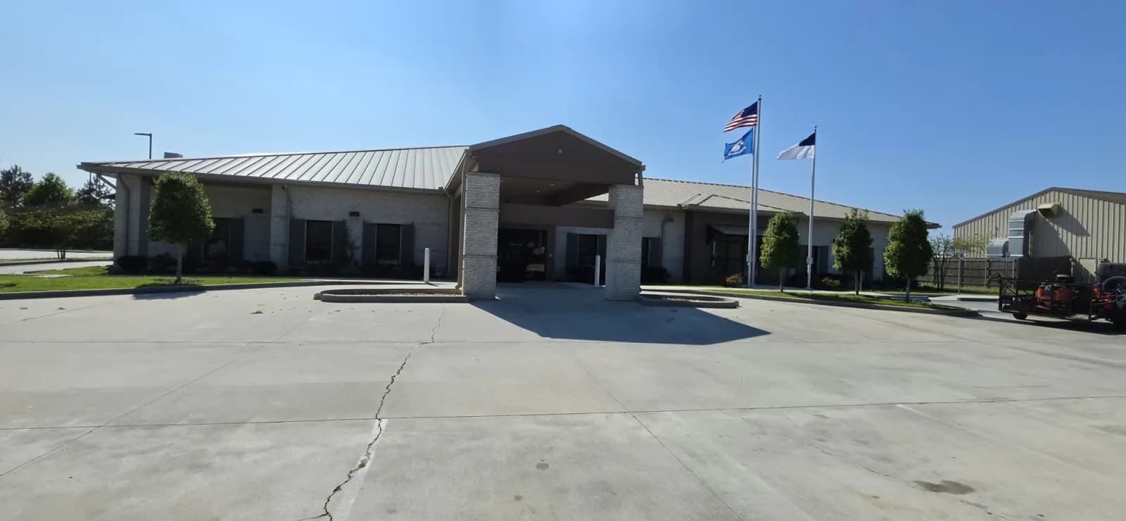 Maintained commercial building lawn and beds with Southern Buck Lawn trailer and zero-turn in view.