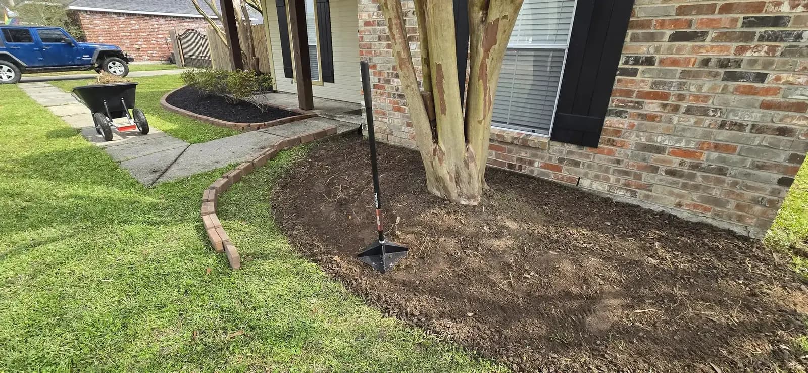 Spade trenching flowerbed edge prep prior to mulch distribution in Louisiana