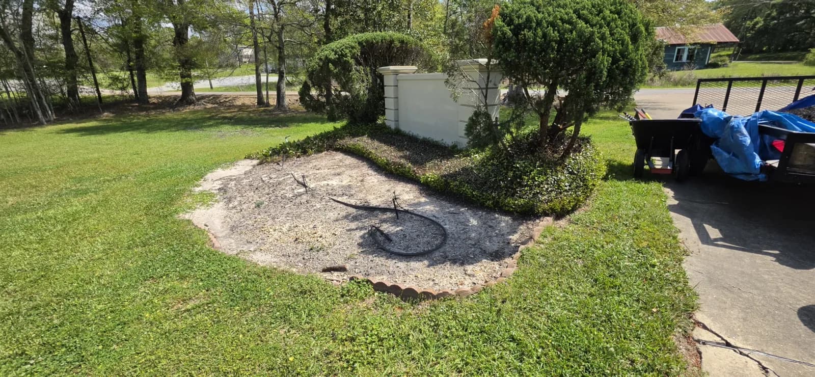 Cleared commercial flower bed with irrigation lines and red scalloped brick edging before mulch.