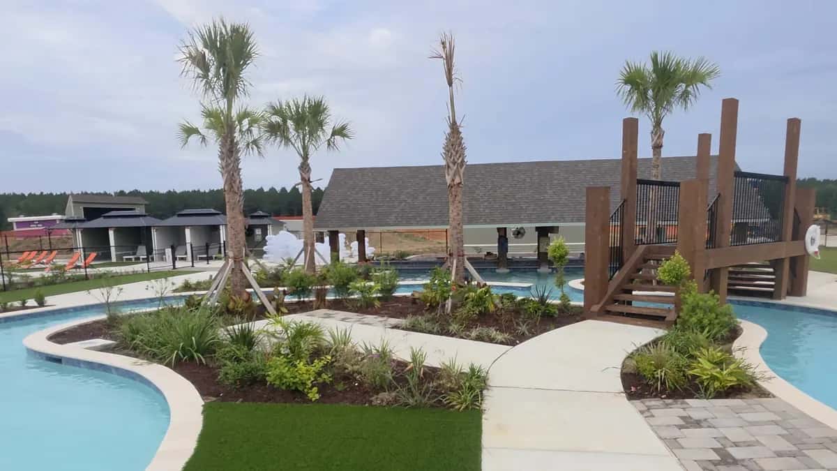Commercial grounds at an RV resort in Satsuma, LA with palm trees, planted beds, and a walkway by the lazy river.