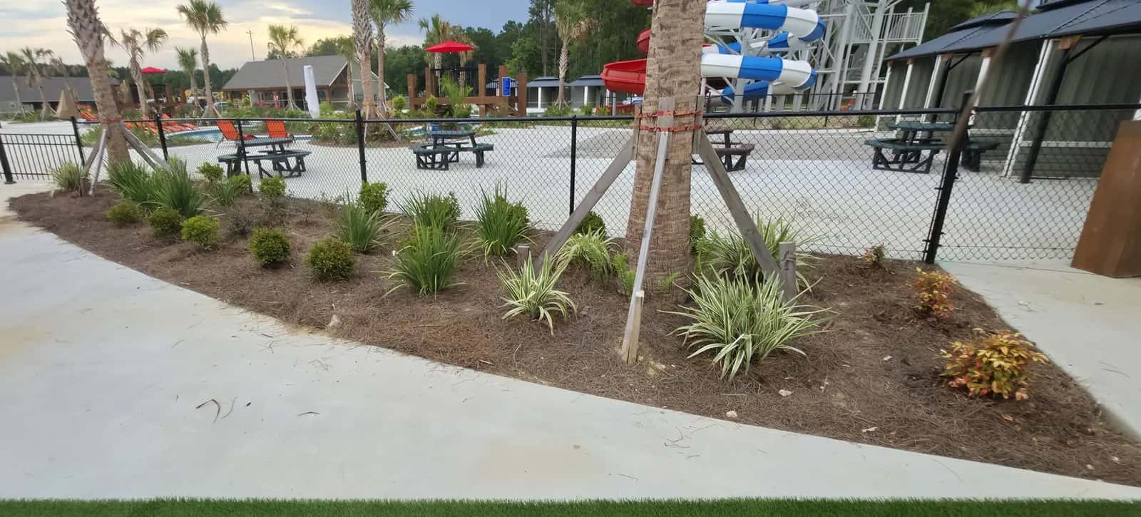 Weed-free commercial landscape bed with fresh soil and young plants beside the pool area at an RV resort in Satsuma, LA.