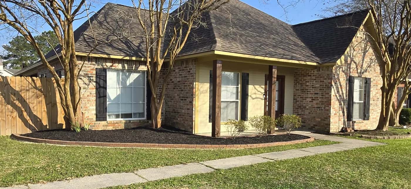 After: Walker, LA front bed installed with fresh mulch, clean edges, and a trimmed crape myrtle along a brick-and-siding house.