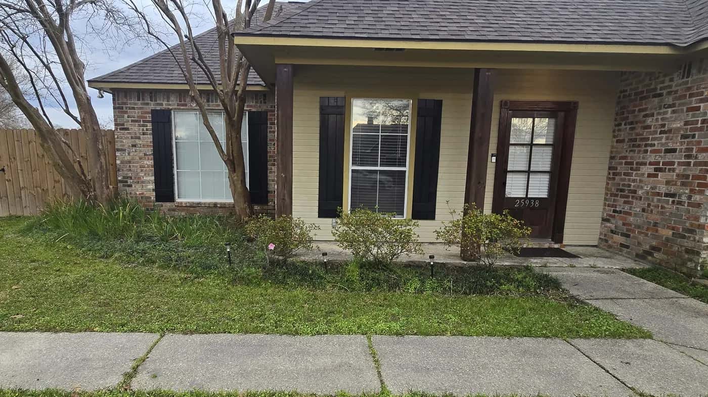 Before: front bed with small scattered shrubs along a brick-and-siding house in Walker, LA.