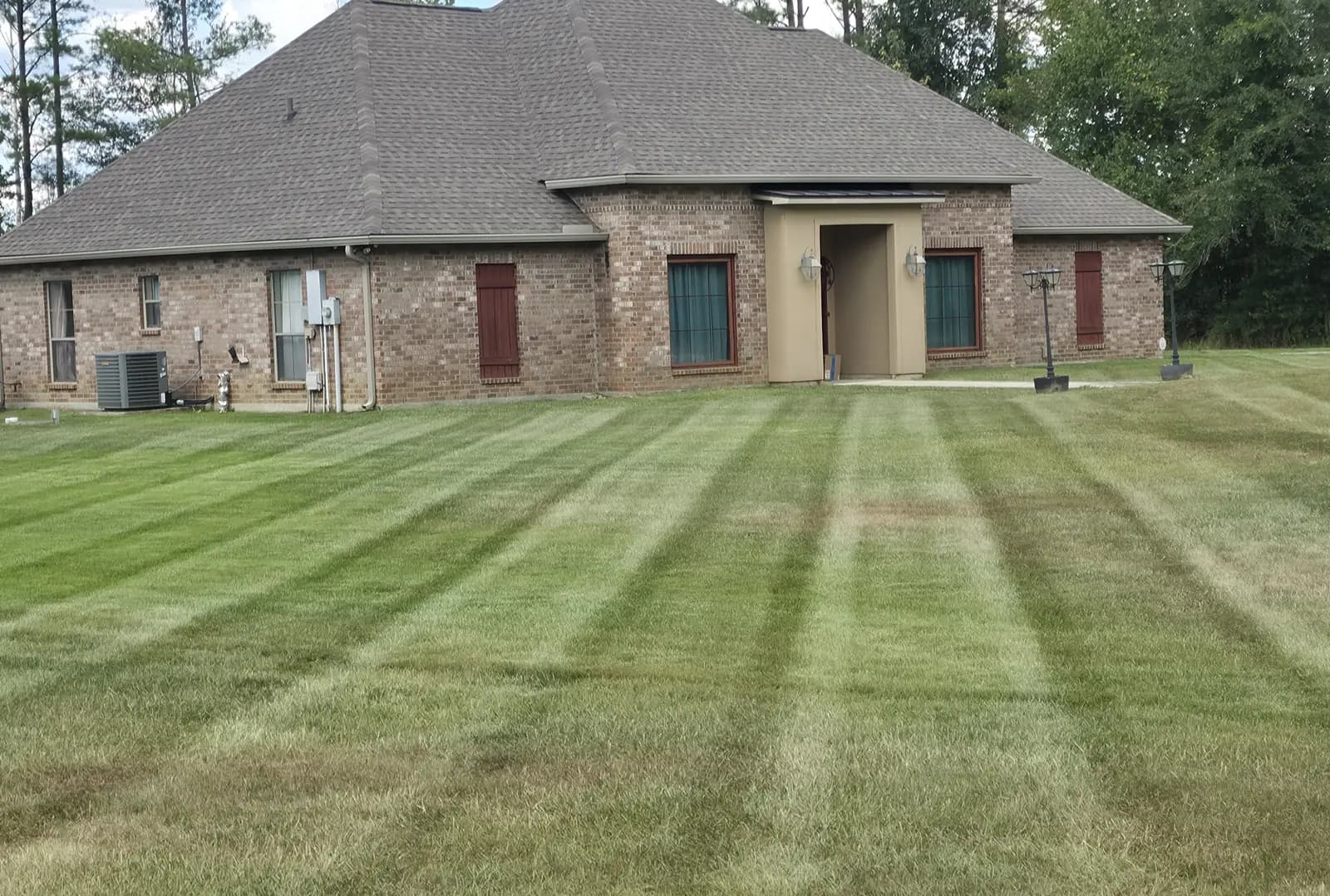 Weekly lawn service on Weiss Rd in Walker, LA: even mowing stripes across the front yard of a brick house.